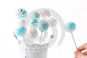 Decorated blue and white cake pops with hand holding.