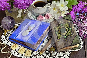 Decorated book and diary with cup of tea and flowers on green witch table