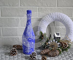 decorated bottle of champagne and a Christmas wreath, a lot of cones nearby