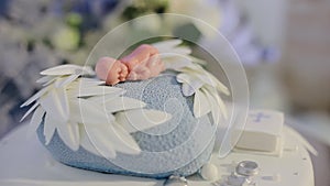 Decorated cake for newborn baby on table with baby doll decorated on top. Cake for christening event