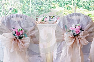 Decorated chairs with white fabric and big gold satin bows with flower.