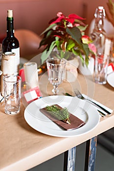 Decorated Christmas holiday table ready for dinner. Beautifully decorated table set with candles, spruce twigs, plates