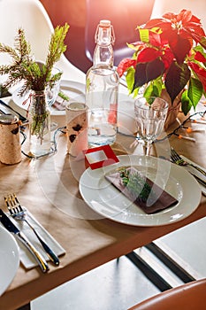 Decorated Christmas holiday table ready for dinner. Beautifully decorated table set with candles, spruce twigs, plates