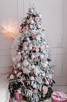 Decorated Christmas interior. Fir-tree decorated garlands with gifts boxes in a white room. Decor. Happy New Year and Merry