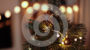 Decorated Christmas tree with big golden star toy on the top against blurred lights on background