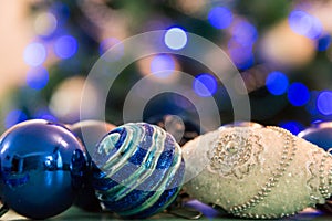 Decorated Christmas tree with blue lights. Christmas balls in the foreground. Blurred image of a Christmas tree in the background