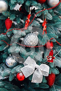 Decorated Christmas tree closeup. Red and golden balls and illuminated garland with flashlights. New Year baubles macro