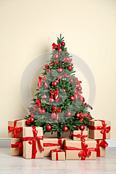 Decorated Christmas tree and gift boxes near wall