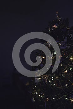 Decorated Christmas tree with lights on a dark background, copy space