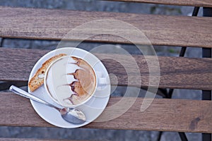 Decorated coffee with cookie and spoon on a wooden table. Close
