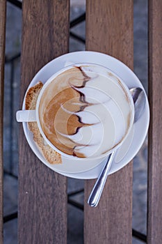 Decorated coffee with cookie and spoon on a wooden table. Close