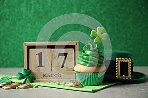 Decorated cupcake, block calendar, hat and coins on grey table. St. Patrick`s Day celebration