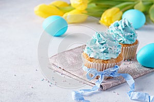 Decorated cupcakes with cream, blue eggs and tulips for Easter