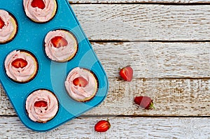 Decorated cupcakes on a white wooden table with strawberries