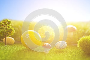 Decorated easter eggs in green grass on sunset sky background.