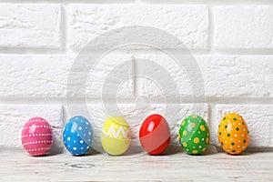 Decorated Easter eggs on table near brick wall