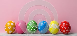 Decorated Easter eggs on table near color wall