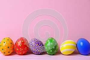 Decorated Easter eggs on table near color wall