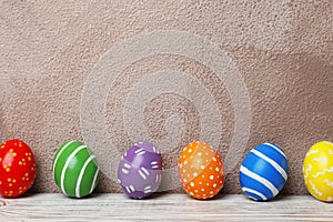 Decorated Easter eggs on table near color wall