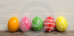 Decorated Easter eggs on table near wooden wall