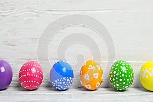 Decorated Easter eggs on table near wooden wall