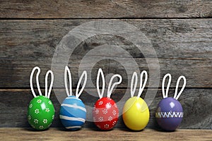 Decorated Easter eggs on table near wooden wall