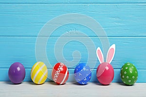 Decorated Easter eggs on table near wooden wall.