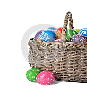 Decorated Easter eggs in wicker basket on white