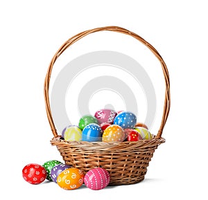 Decorated Easter eggs in wicker basket on white background