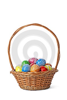 Decorated Easter eggs in wicker basket on white