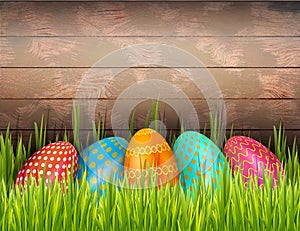 Decorated Easter eggs on wooden background with green grass and copy space. Banner, poster with copy space.