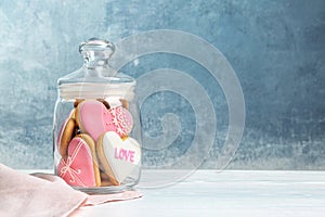 Decorated heart shaped cookies in glass jar on table