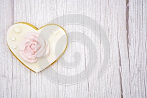 Decorated heart shaped organic cookie with beautiful rose on wooden background, top view. Valentine's day treat.