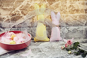 Decorated home for Easter: bright pink bowl with colorful eggs and pink fluffy feathers, crafting soft bunnies, pink