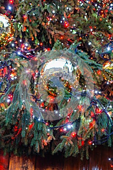 Decorated illuminated outside christmas tree showing reflection of Covent Garden, London, in a golden bauble