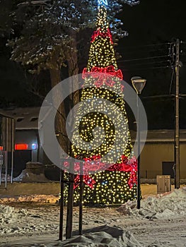 A decorated and lit Christmas tree in the parking lot of a village church in Poland