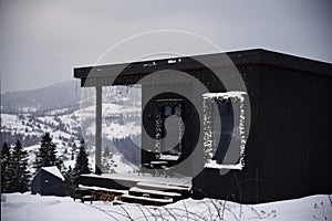 Decorated modern black small cottage on snowy mountains