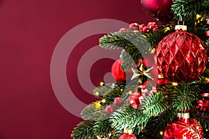 Decorated with ornaments and lights Christmas tree on red background. Merry Christmas and Happy Holidays greeting card