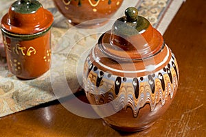 Decorated pottery jar on a table with embroidered mat