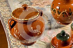 Decorated pottery sugar bowl on a table with embroidered mat