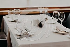 Decorated served table with cutlery and glasses for wedding reception or other festive event. Round Table with cutlery, white tabl