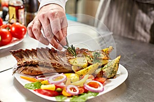 Decorated with a sprig of rosemary. the chef prepares in the restaurant. Grilled rack of lamb with fried potatoes and