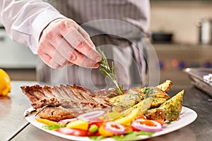 Decorated with a sprig of rosemary. the chef prepares in the restaurant. Grilled rack of lamb with fried potatoes and