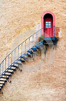 Decorated stairs leading to a door in terracotta wall