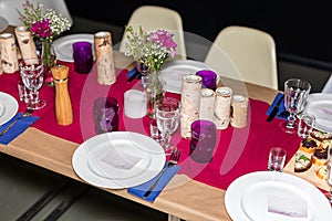 Decorated table ready for dinner. Beautifully decorated table set with flowers, candles, plates and serviettes for wedding or anot