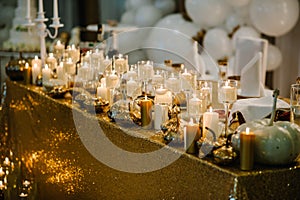 Decorated table for wedding. White balloons, candles, autumn leaves and small pumpkins. Autumn location and Halloween decor.