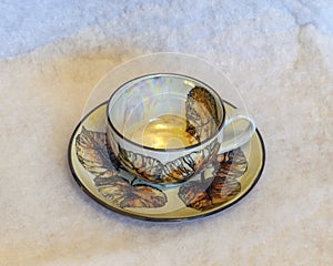 Decorated tea mug with saucer on a white background