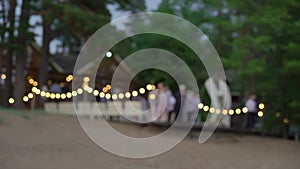 Decorated wedding ceremony outside. Arch, chairs and string lights blur.