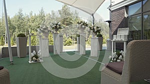 Decorated wedding ceremony reception on terrace. On columns stands flowerpots