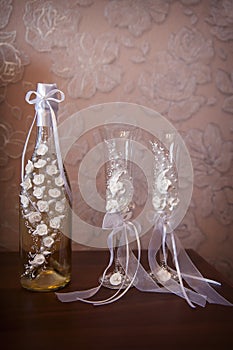 Decorated wedding glasses and bottle of champagne